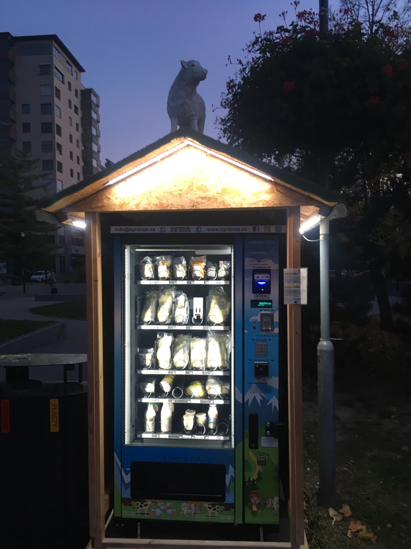 Osvietený mliečny automat Syromat vonku v parku večer